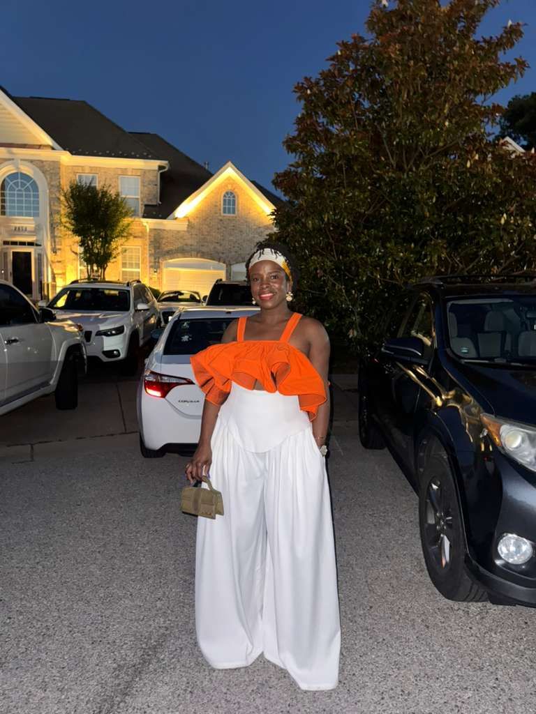 Minnie in a tangerine ruffle top and ivory palazzo trousers she made herself